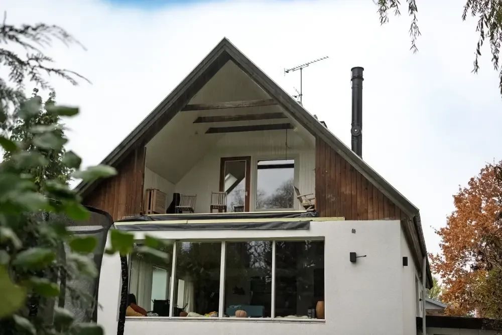 Gavl med mørkbejdset træbeklædning, gammel skorsten og antenne